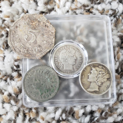 Ein Haufen Münzen, gefunden von Hunter T. einschließlich einer Barber-Münze aus dem Jahr 1916, ein Merkur-Zehncentstück aus dem Jahr 1944, Eincentstück mit Indianerkopf aus dem Jahr 1891, und eine 5-Cent-Handelsmarke.